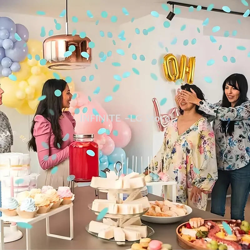 A woman is using confetti cannons to reveal a gender, surrounded by pink and yellow balloons.