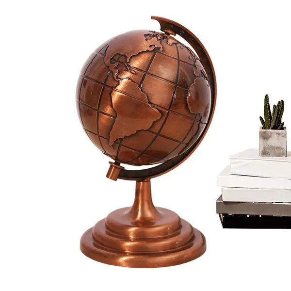 A vintage bronze globe with a world map mounted on a stand, next to a small potted succulent plant.