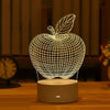 A white wireframe apple night light with a leaf design sits on a wooden surface.