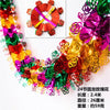 A close-up of a shimmering tinsel garland ribbon featuring various colors like pink, gold, green, and red, with a small circu
