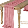 A pink semi-sheer gauze table runner draped over a wooden table.