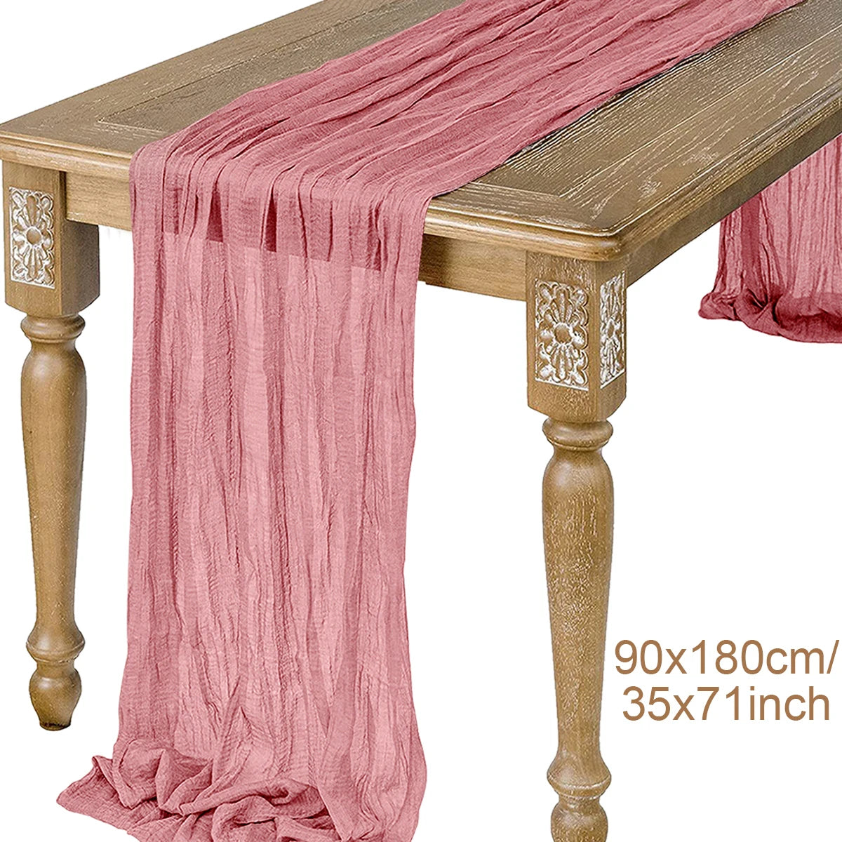 A pink semi-sheer gauze table runner draped over a wooden table.