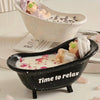 A black silicone mold shaped like a bathtub holds white wax or candle, with a small figure resting inside.