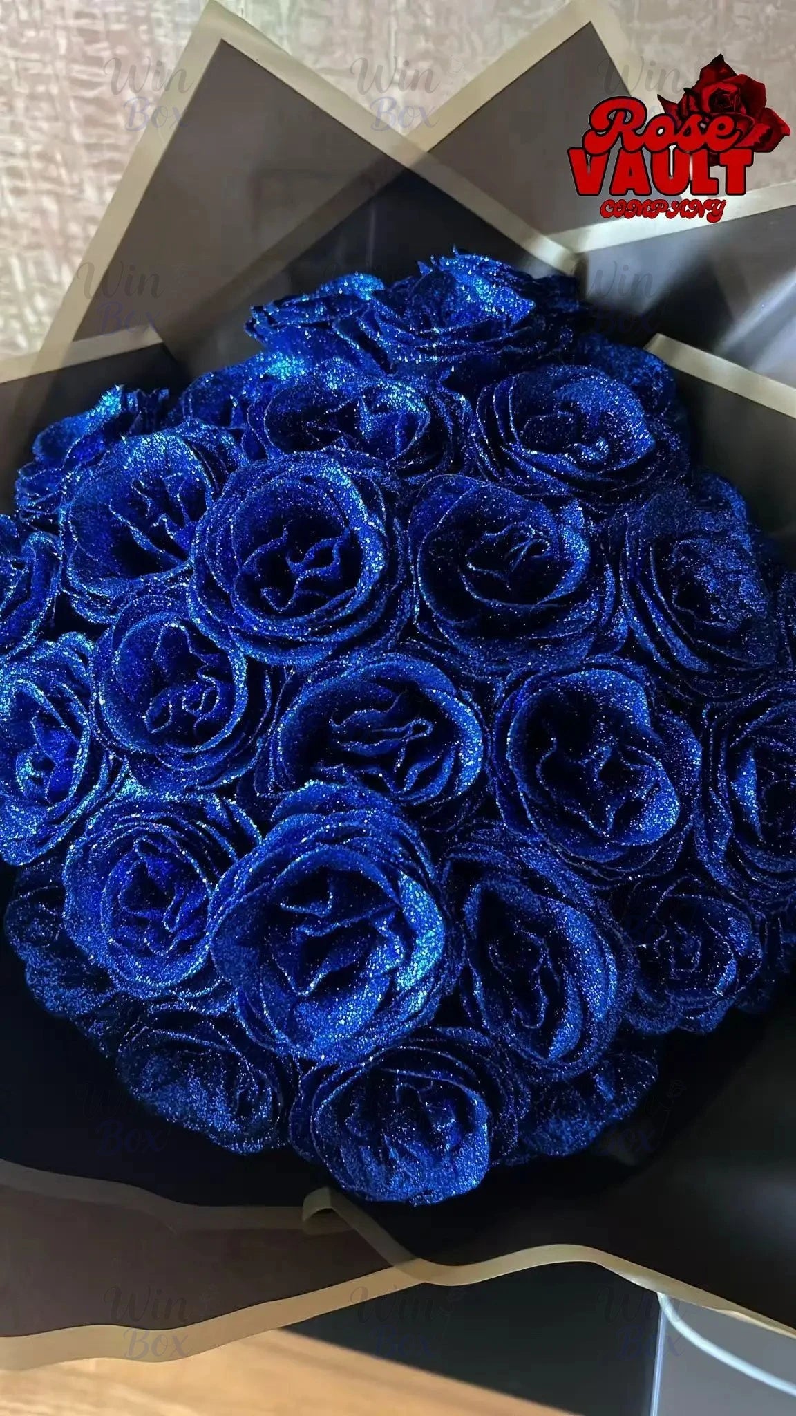 A bouquet of deep blue glitter artificial roses displayed in a dark box.