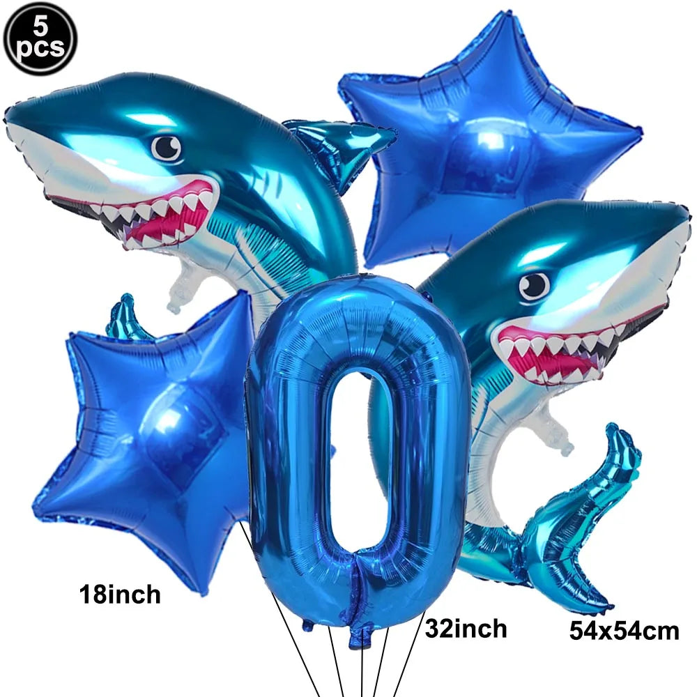 A set of blue shark foil balloons, including a shark shape and the number zero, for an ocean-themed party decoration.