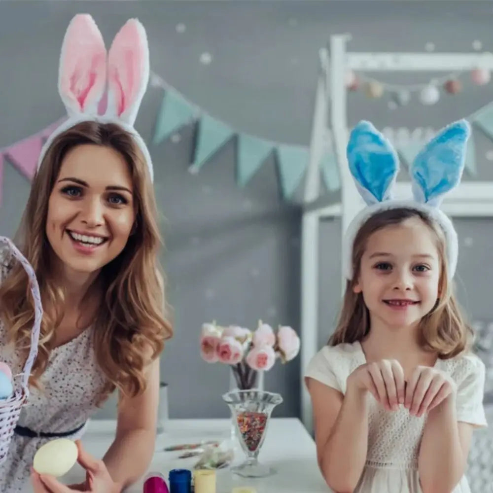 A woman and a girl smiling while wearing colorful bunny ear headbands in a light-colored room.