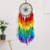 A colorful feather dream catcher pendant with multicolored feathers hanging on a white wall.