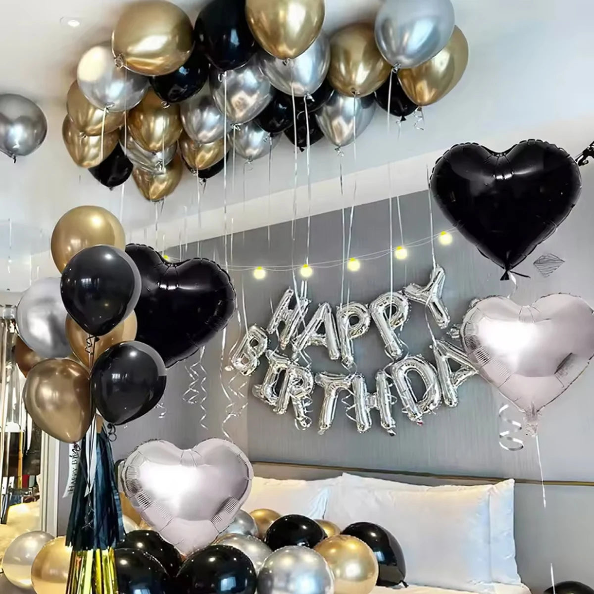 A display of black, gold, and silver balloons with a silver banner decoration for a party.