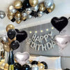 A display of black, gold, and silver balloons with a silver banner decoration for a party.
