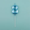 A blue number eight candle on a thin stick against a light teal background.