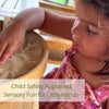 A young girl is using a wooden sensory sand table for play and relaxation.