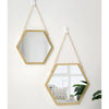 A gold-framed hexagon decorative wall mirror hanging by a delicate chain.