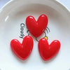 A set of three glossy red heart-shaped fridge magnets arranged on a white plate.