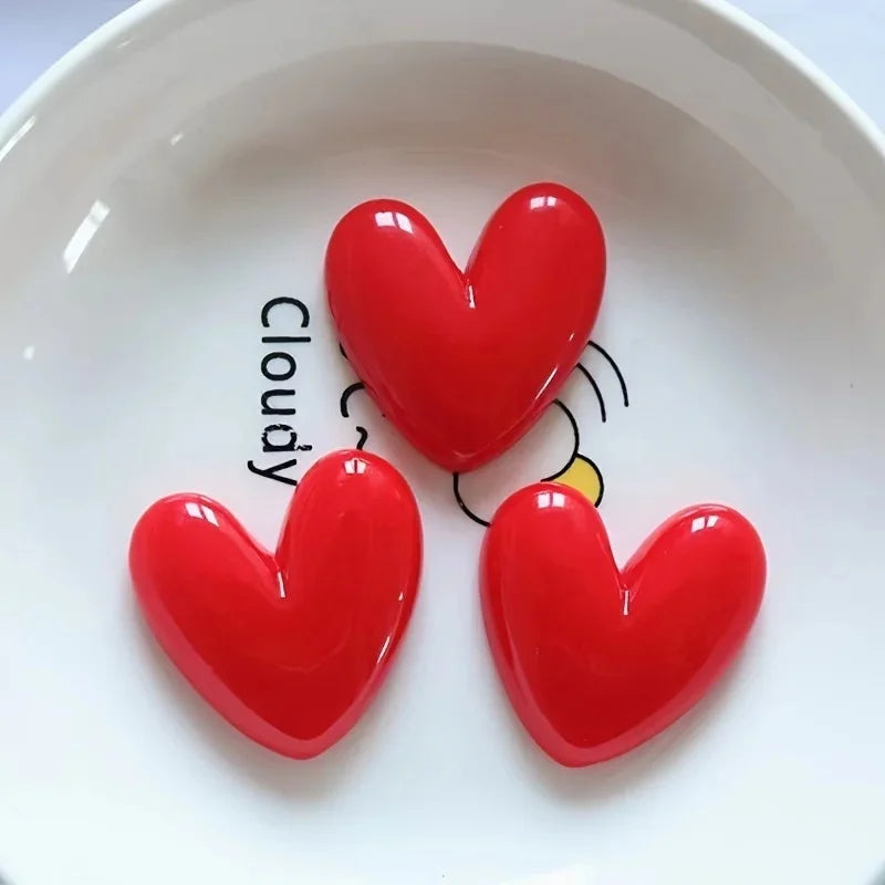 A set of three glossy red heart-shaped fridge magnets arranged on a white plate.