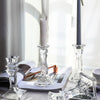 Elegant clear glass pillar candle holder with a white candle on a light gray surface.