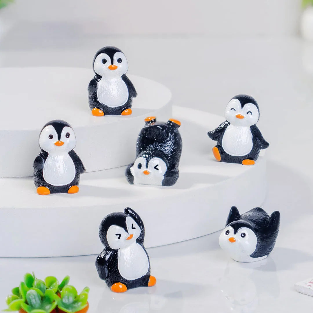 A collection of cute cartoon penguin resin figurines in black and white sitting on a white surface.