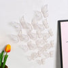 A set of white 3D hollow butterfly wall decals displayed against a white background next to a yellow tulip.