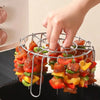A hand is placing food onto a stainless steel vertical skewer rack for an air fryer.