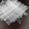 A pile of clear disposable drinking straws laid diagonally on a dark surface.