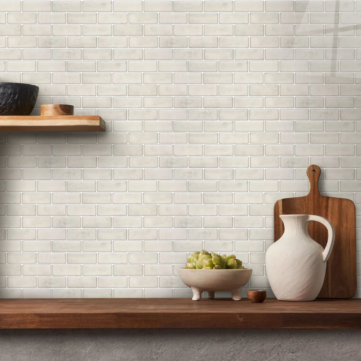 A white subway tile wall is displayed with wooden cutting boards and a white ceramic pitcher and bowl.