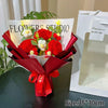 A bouquet of red and white crochet flowers tied with a red ribbon displayed in a white gift box.
