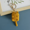 A handcrafted yellow crochet cat keychain pendant attached to a gold-colored ring.