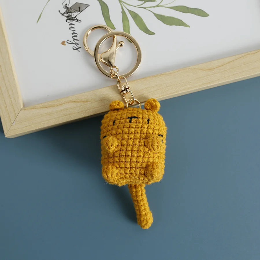 A handcrafted yellow crochet cat keychain pendant attached to a gold-colored ring.