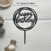 Black acrylic birthday cake topper with gold lettering on a white wooden background
