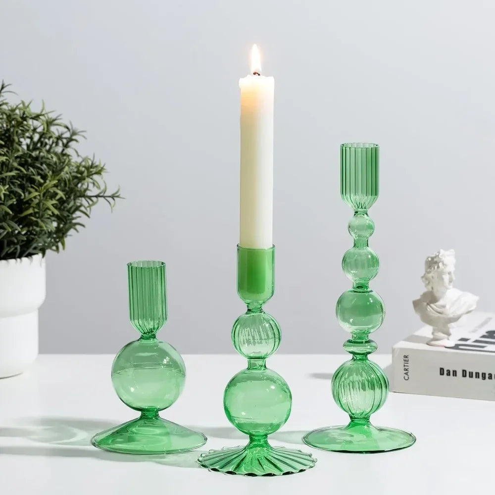 A set of three green wavy glass taper candle holders displayed on a white surface.