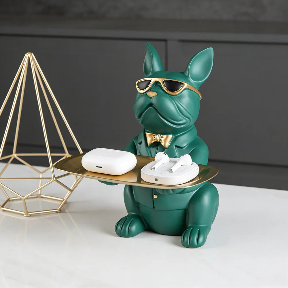 A green bulldog figurine wearing sunglasses is sitting on a gold tray.