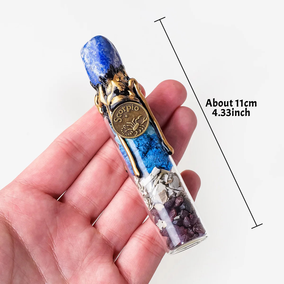 A hand holds a natural crystal zodiac wishing bottle featuring blue and gold elements and raw healing stones.