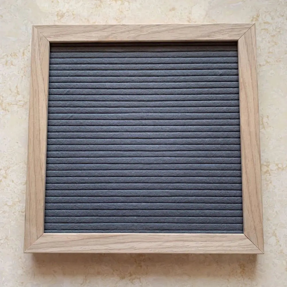 A rectangular wooden letter message board with a dark gray slatted surface and a light wood frame.