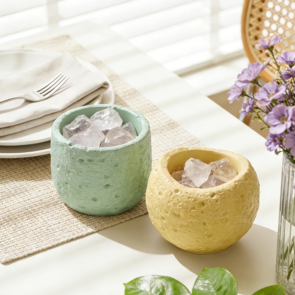 A light green silicone mold filled with clear crystals sits next to a yellow textured mold on a white table.