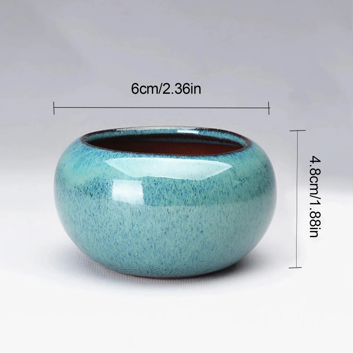 Maceta de suculenta de cerámica redonda con esmalte azul y borde marrón sin esmaltar, vista de perfil.