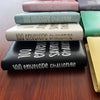 A stack of 100 Envelope Challenge binders in various pastel and dark colors, showing the envelopes on top.