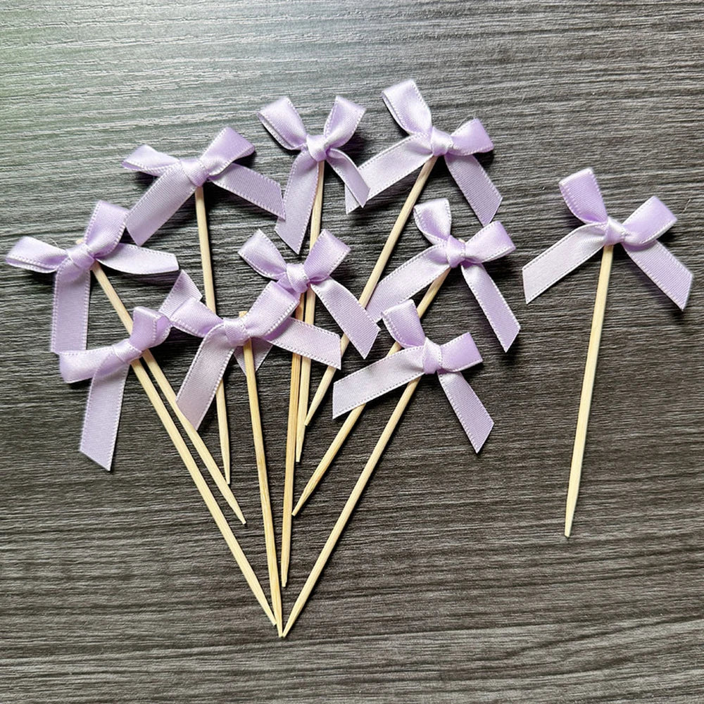 A set of purple ribbon bows on wooden sticks used as cupcake toppers for parties.