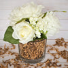 Glasgefäß mit zerfetztem Papier-Füllmaterial für Veranstaltungen, umgeben von grünen Blättern und weißen Blumen.
