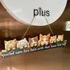 A wooden sign featuring several adorable cats with orange and white fur, hanging on a wall.