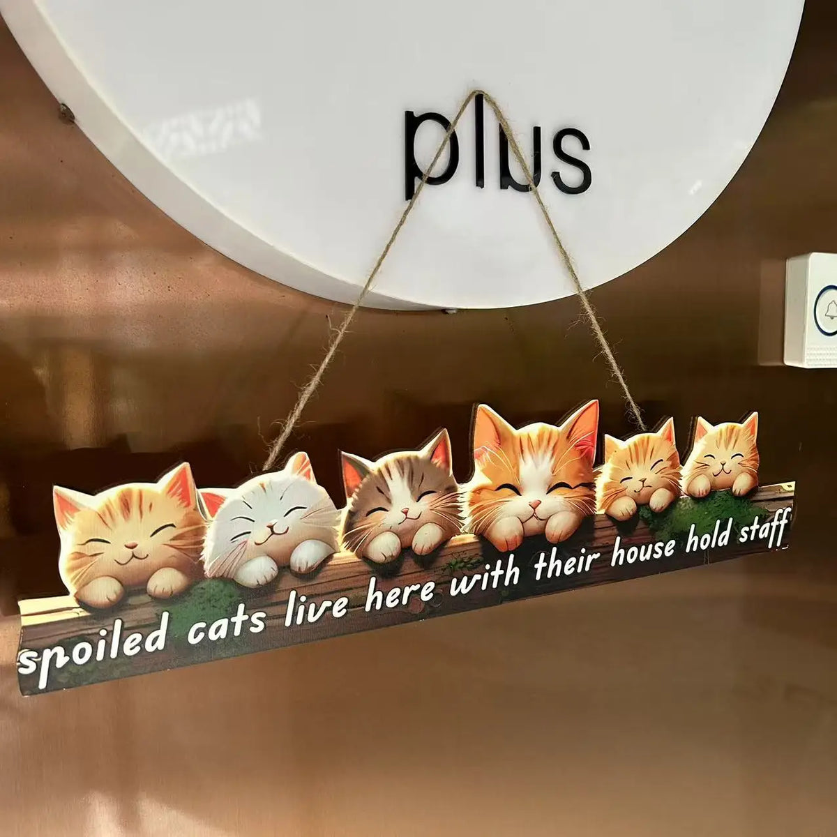 A wooden sign featuring several adorable cats with orange and white fur, hanging on a wall.