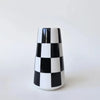A ceramic tabletop vase with a black and white checkerboard pattern, standing upright against a white background.