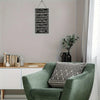 A green armchair in a room with a framed Islamic calligraphy sign on the wall.