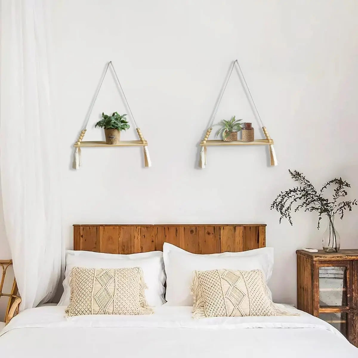 A bedroom setting featuring two handmade macrame wood wall shelves with tassels above a white bed.