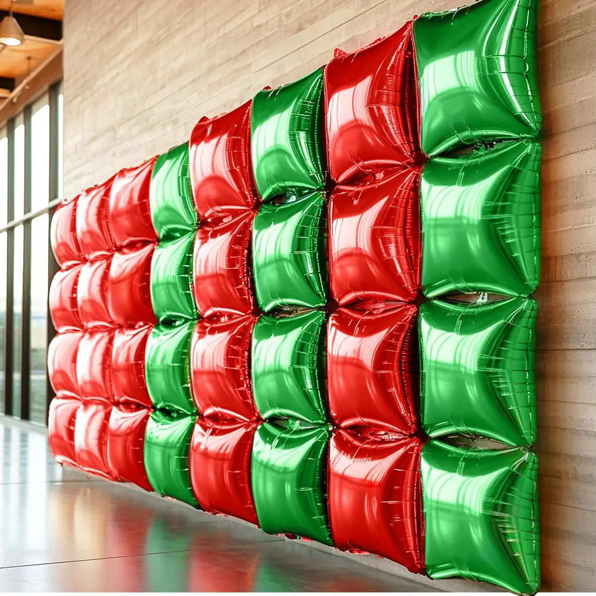 A vertical wall display of red and green double-sided square foil balloons for celebrations.