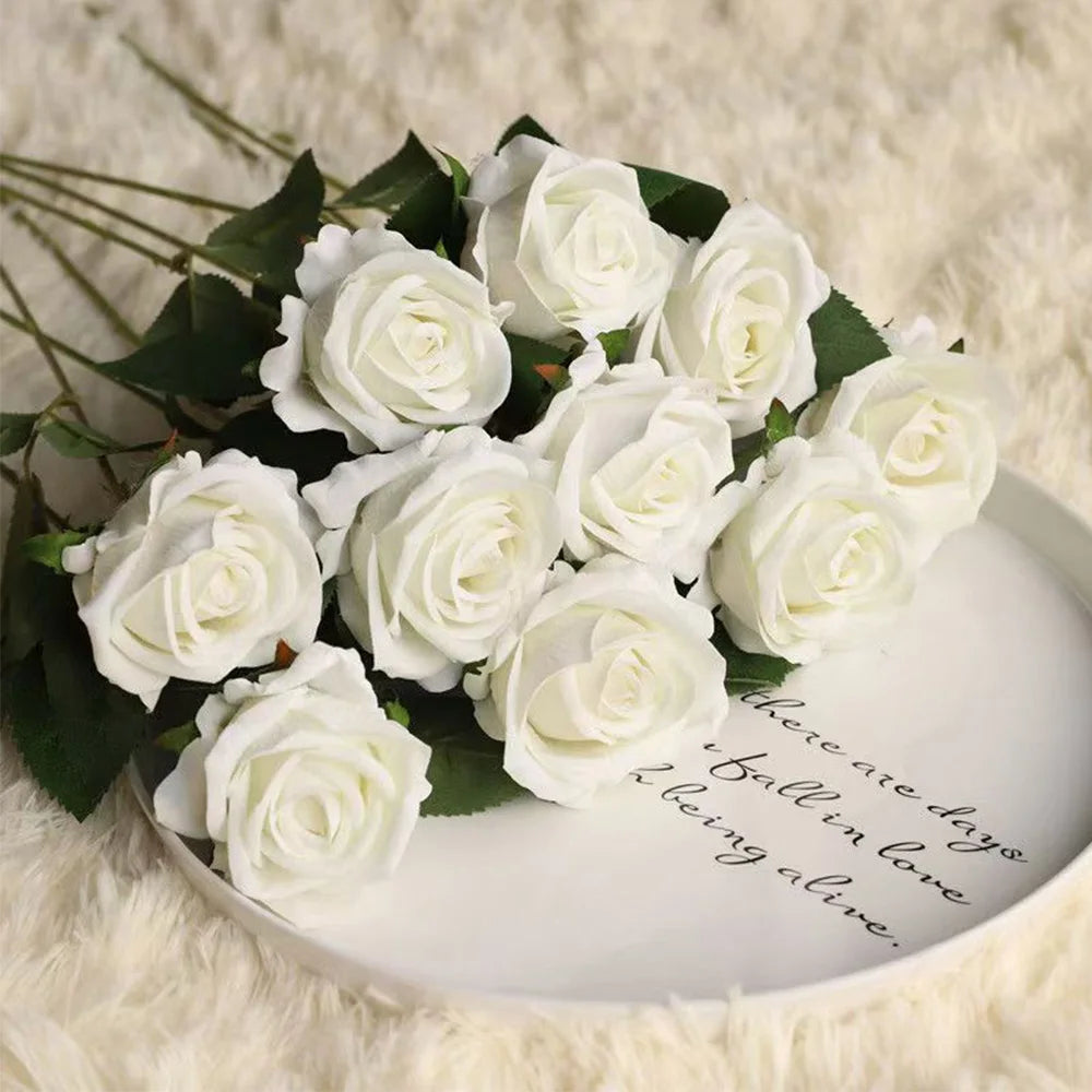 A bouquet of white artificial roses arranged on a white plate, set against a fluffy white background.