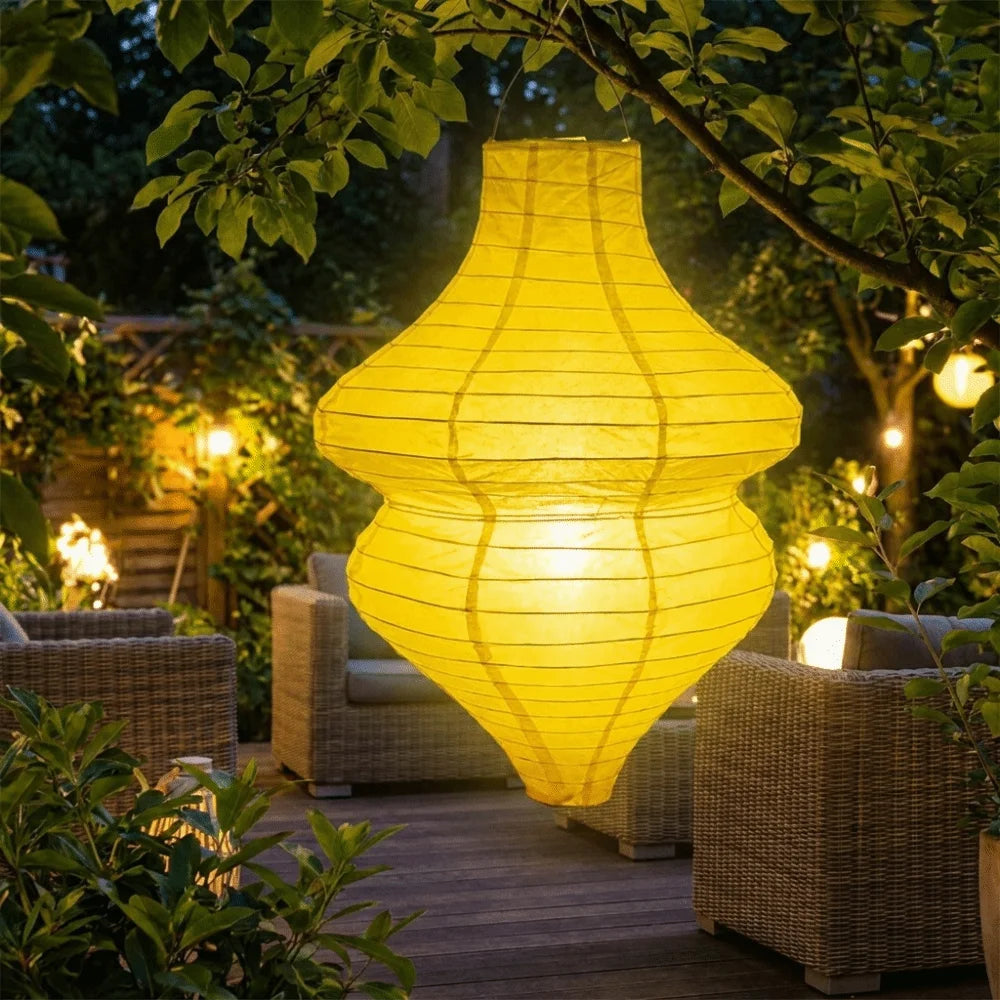 Linterna de flor vintage de color amarillo brillante, artesanal y hecho a mano, colgando de una rama de árbol en un jardín al