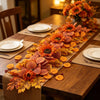 An arrangement of dried autumn leaves and orange sunflowers displayed on a wooden table.