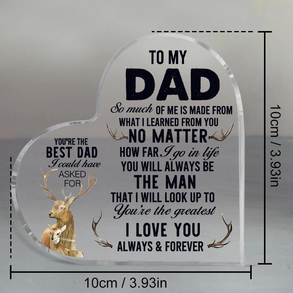 A clear heart-shaped glass sign engraved with a message to dad and featuring a deer antler design.