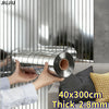 A hand is holding a cylindrical metal strip with a mirror effect finish against a vertical metallic background.