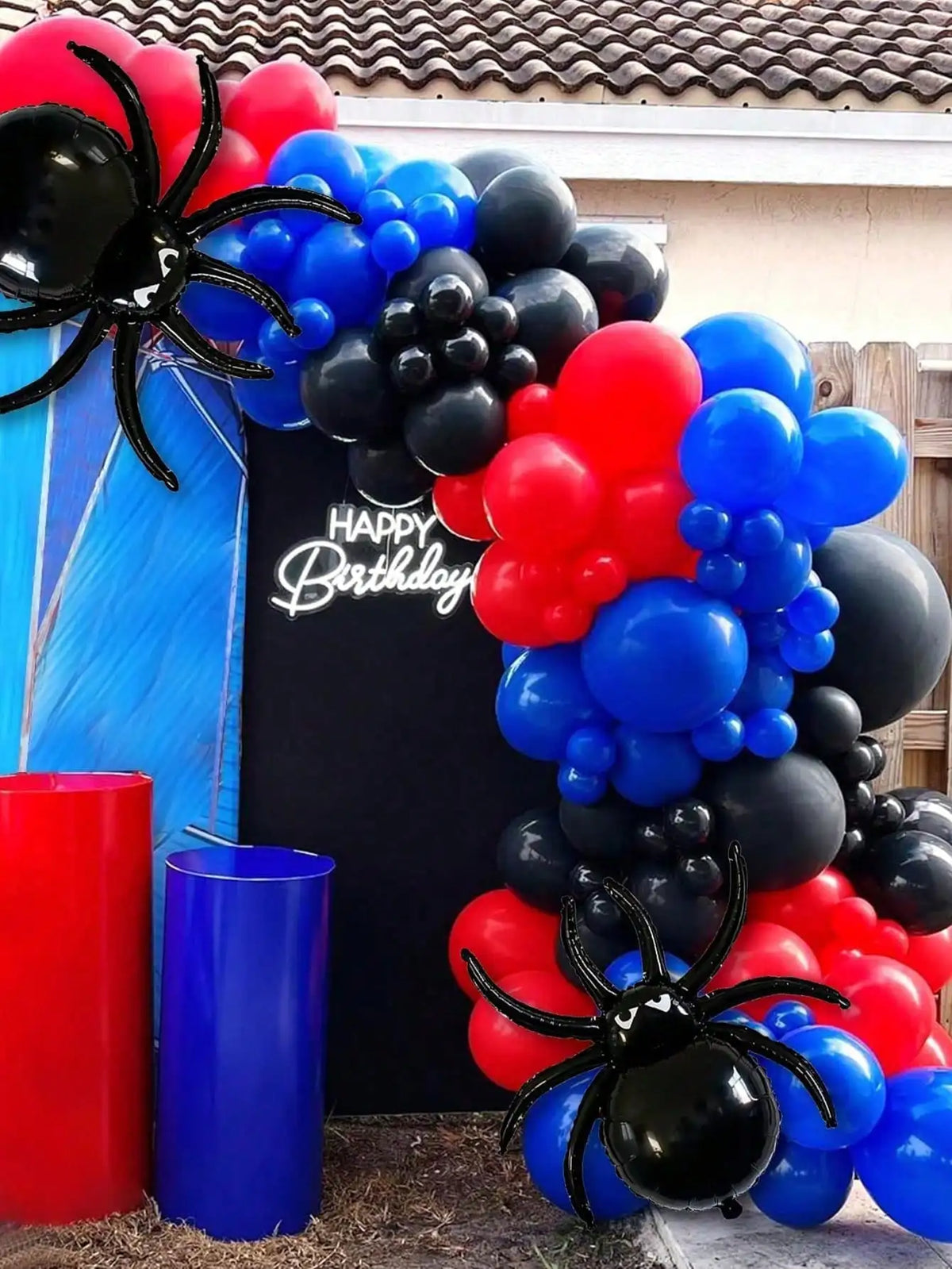 Une arche de ballons noire, rouge et bleue en forme d'araignées et de grappes.