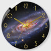 A round wall clock face featuring a dark background and a colorful spiral galaxy design.